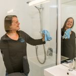 hotel cleaner wiping bathroom mirror